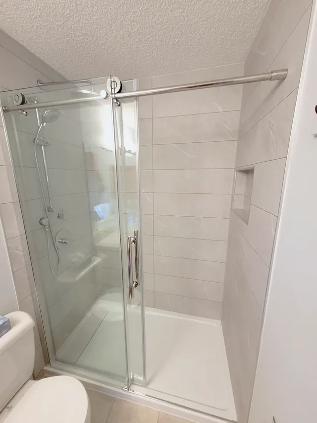Walk-in shower with grout-free tile-less walls and sliding glass, Calgary